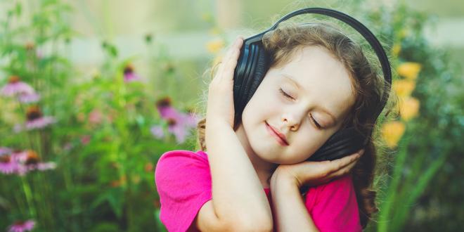 a little girl bopping to her headphones in a field of flowers