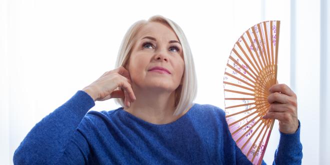 Woman fanning her face with a delicate fan.