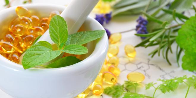 Soft gel supplements in a mortar surrounded by herbs with chemical structure drawings