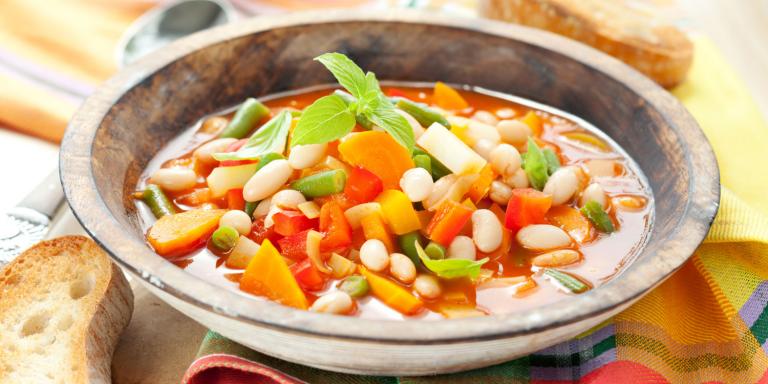 A hot bowl of soup with vegetables and pasta.